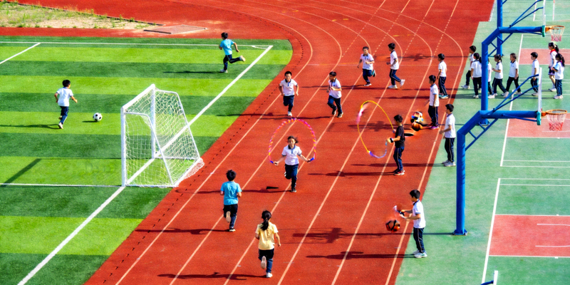 现代化学校操场，学生正在进行体育课活动